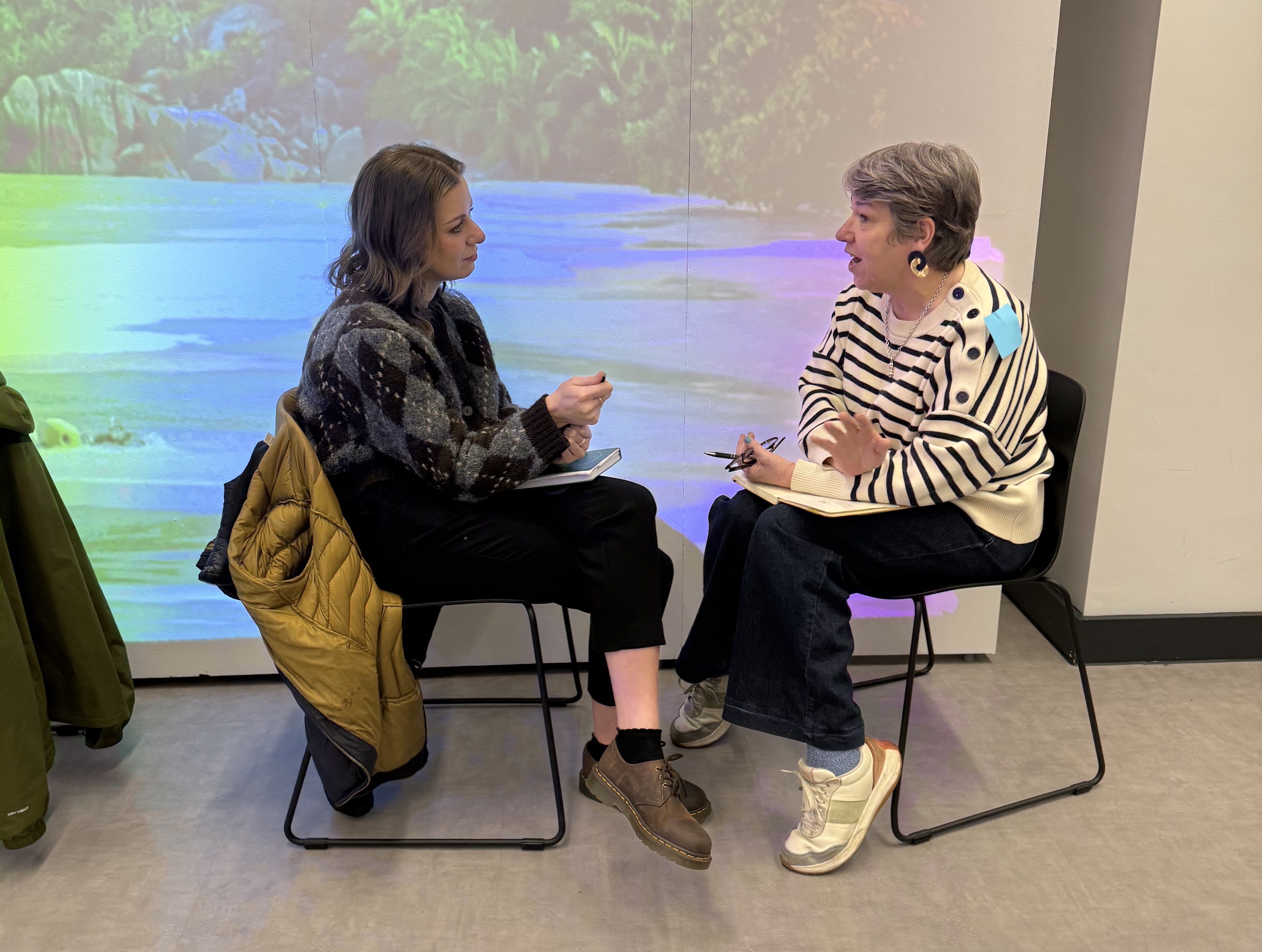 Two people sit facing each other talking