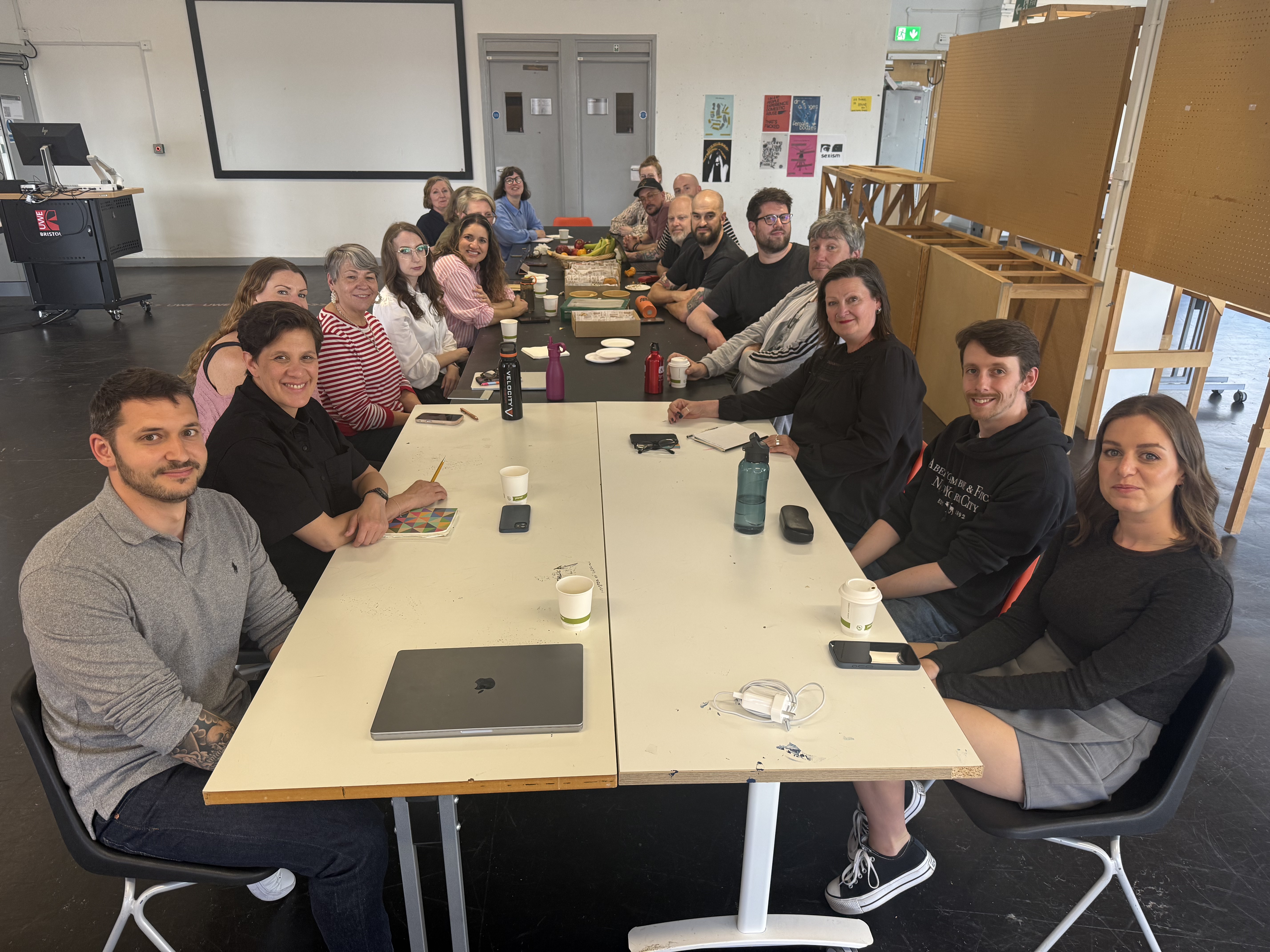 A group of people sit around a long table looking towards the camera and smiling