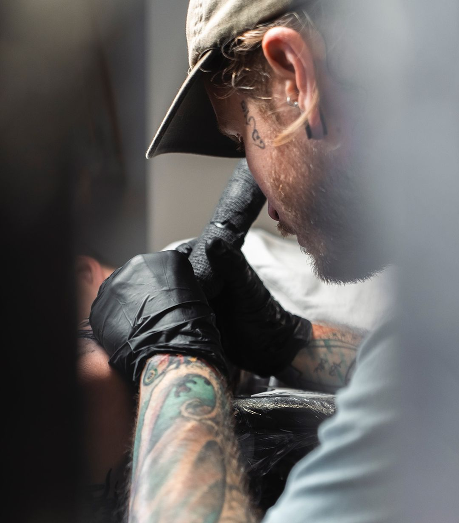 Image of tattoo artist tattooing a client