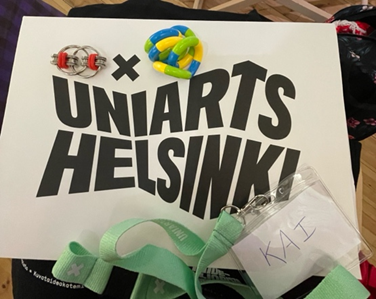 Fidget toys placed on top of a paper file that reads &lsquo;UNIARTS HELSINKI&rsquo;, with a name tag with a lime green strap and name &lsquo;KAI&rsquo;.&nbsp;