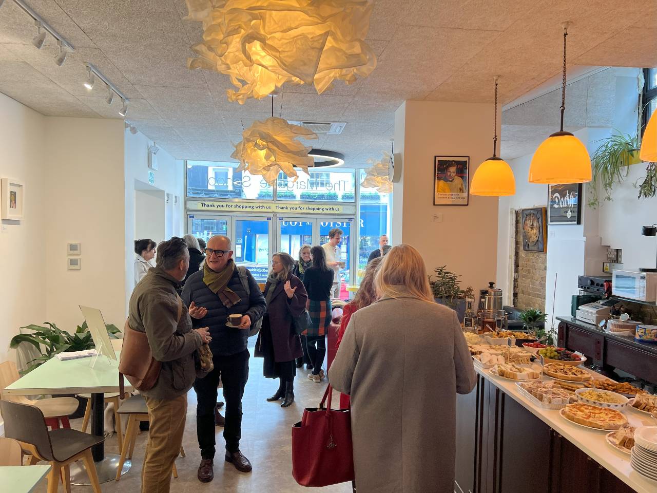 people gathered and talking in the Margate school cafe with a counter of food on the right