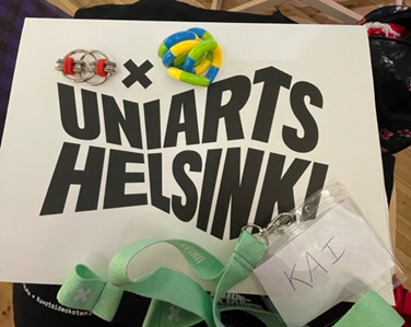 Fidget toys placed on top of a paper file that reads ‘UNIARTS HELSINKI’, with a name tag with a lime green strap and name ‘KAI’. 