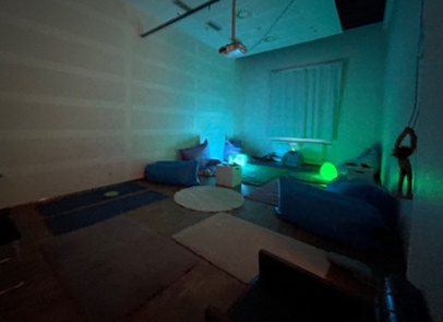 Sensory room, with low blue-green lighting, soft furnishings and soft toys