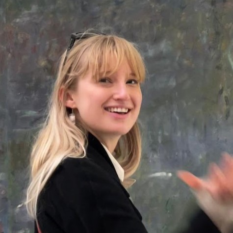 A headshot taken from the side of a woman with blond hair wearing a black jacket.